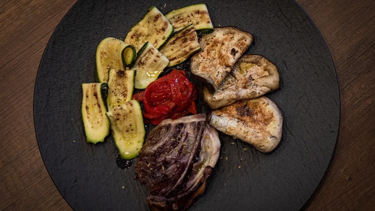 A delectable assortment of grilled vegetables on a rustic black plate, accented with olive oil and spices.